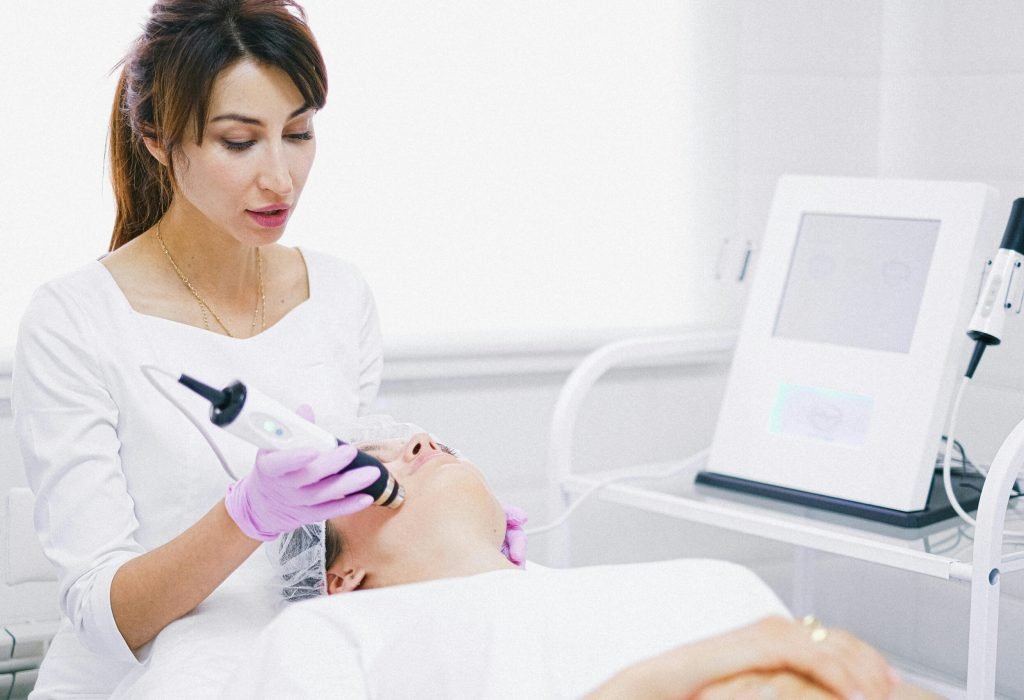 Aesthetician providing a laser facial treatment to a patient in a spa clinic setting.